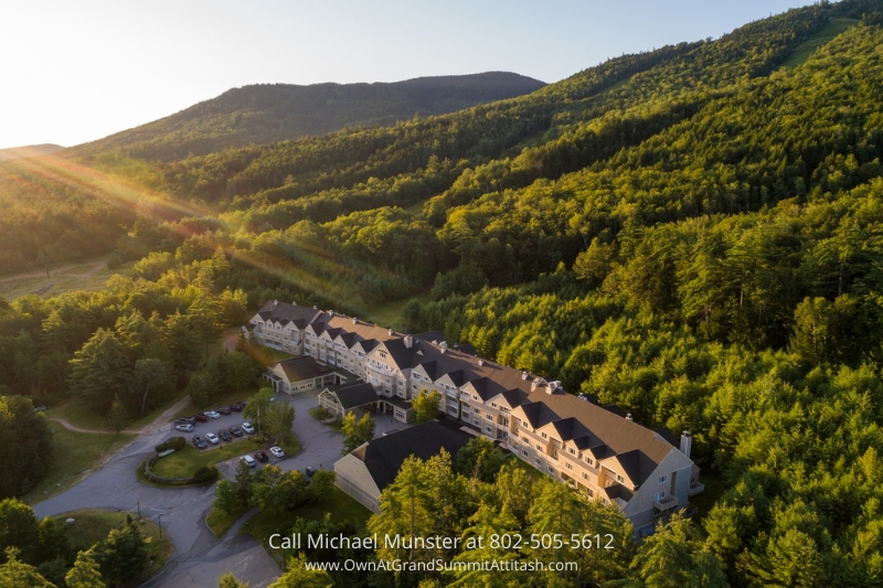 A stunning aerial view of the Grand Summit Hotel nestled amidst lush green mountains, showcasing its beautiful architecture and scenic surroundings bathed in the golden glow of the setting sun. This image captures the serene and luxurious experience the Grand Summit Hotel offers.