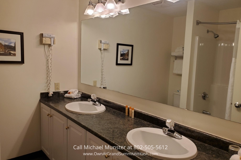 Elegant bathroom at the Grand Summit Hotel featuring a spacious countertop with two sinks, large mirror, and soft lighting, offering guests a modern and comfortable space to freshen up during their stay.