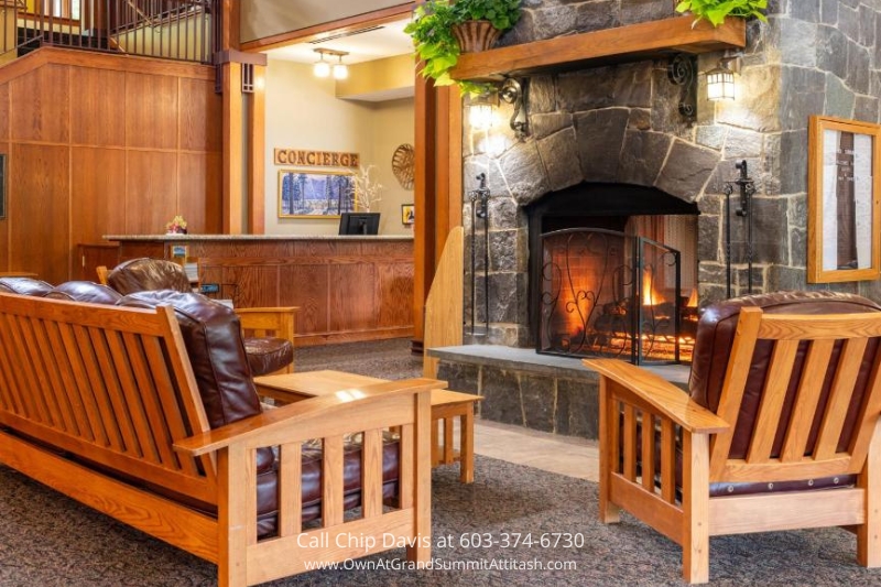 The cozy lobby of the Grand Summit Hotel, featuring a large stone fireplace, comfortable wooden seating, and a warm ambiance for guests to relax in.