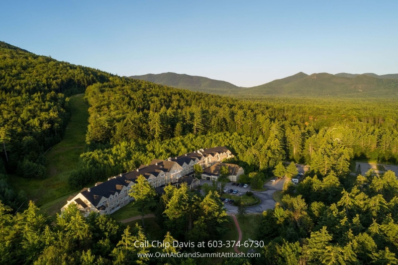 A breathtaking aerial view of the Grand Summit Hotel at sunset, nestled amidst lush green mountains and serene surroundings in Bartlett, NH.