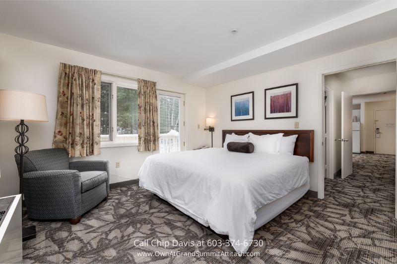 Bright and cozy bedroom in a Grand Summit Hotel unit, featuring a plush king-size bed, elegant decor, and large windows offering views of the surrounding natural beauty in Bartlett, NH.