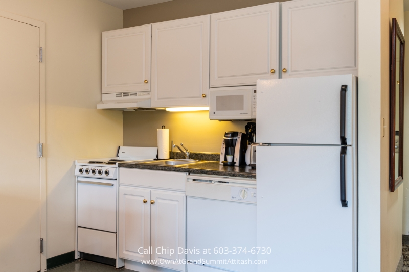 Fully equipped kitchen in a Grand Summit Hotel resort unit, designed with modern appliances, white cabinetry, and a compact layout for guest convenience.