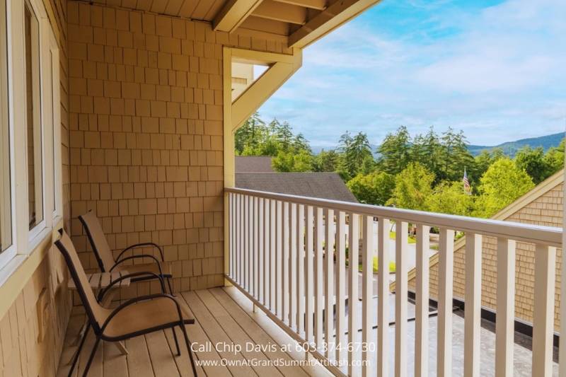 A private deck at the Grand Summit Hotel unit, offering comfortable seating and spectacular views of the lush green landscape and surrounding mountains.