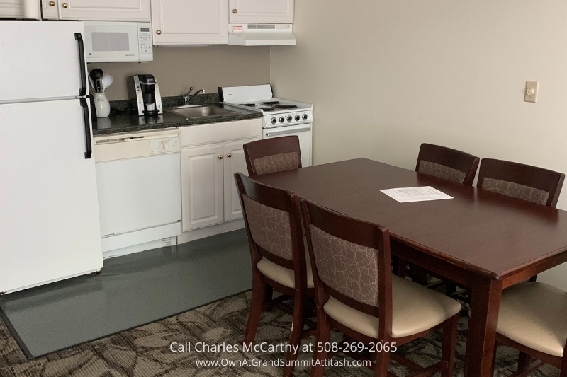 Fully equipped kitchen and dining area in a suite at the Grand Summit Hotel, featuring a dining table with chairs and modern appliances for a convenient stay.