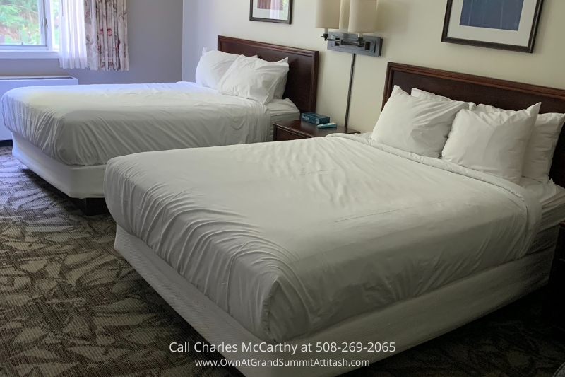 Spacious double queen bedroom at the Grand Summit Hotel, offering cozy beds, a seating area, and large windows with picturesque mountain views.