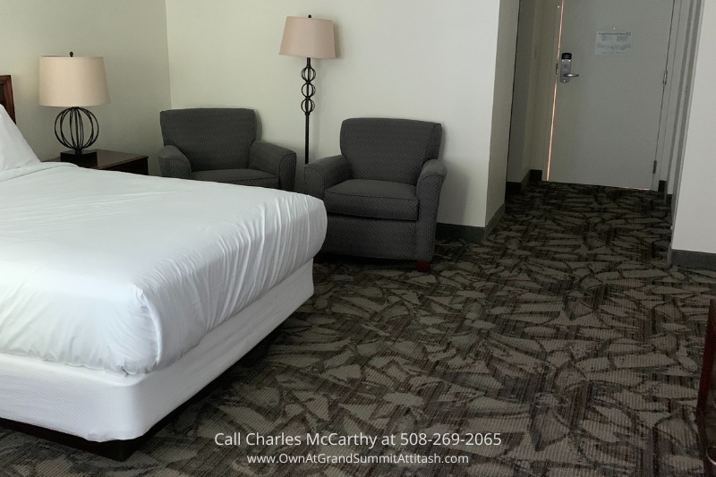 Comfortable living room inside a suite at the Grand Summit Hotel, designed with plush seating, a large window overlooking the mountains, and space for relaxation.