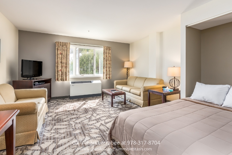 A cozy hotel room at the Grand Summit Hotel featuring a comfortable bed, a stylish couch, and a modern television for entertainment.