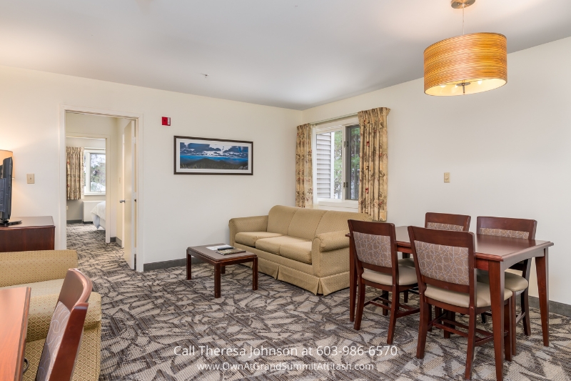 Spacious living room in Unit 149 Interval 4 at the Grand Summit Hotel, Bartlett, NH, furnished with a comfortable sofa set, dining table, and large windows offering scenic views.