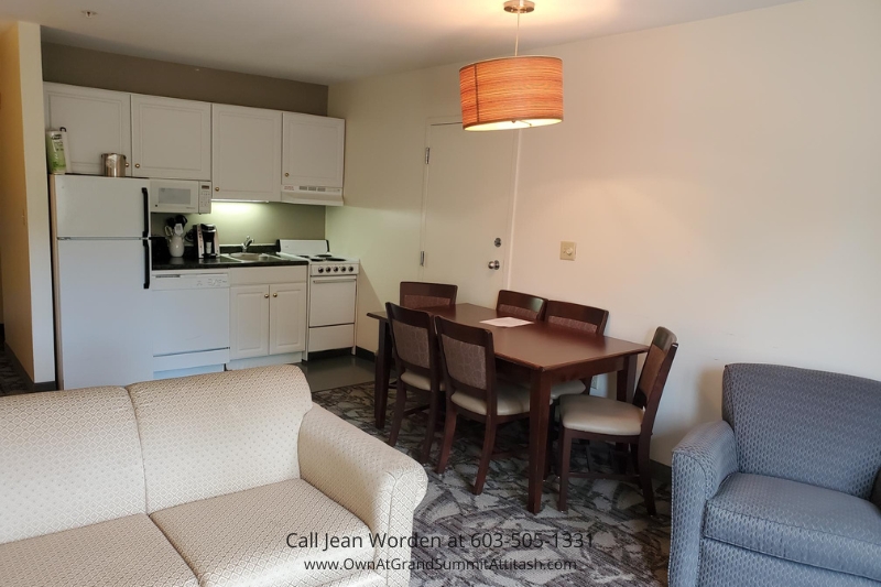 Living space with kitchen in a Bartlett NH Resort Living Unit, featuring a cozy couch, dining area, and well-equipped kitchen with appliances, perfect for a relaxing stay.